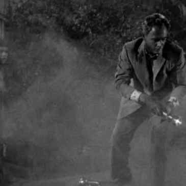 Man with a flashlight in a foggy cemetary