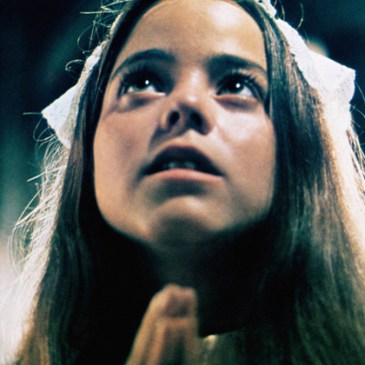 close up of a girl looking up with hands clasped in prayer