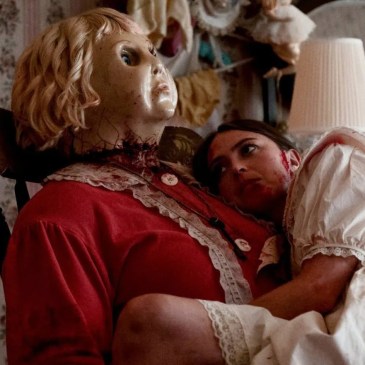 large woman in a doll mask holding a woman while in a rocking chair