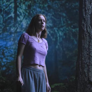 Woman standing in dark woods
